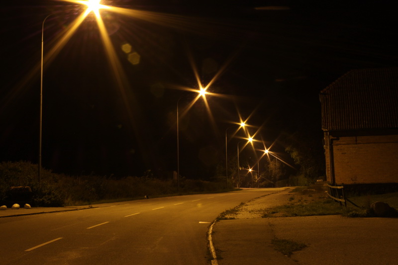 Gatubelysning som lyser i mörkret längs med en gata