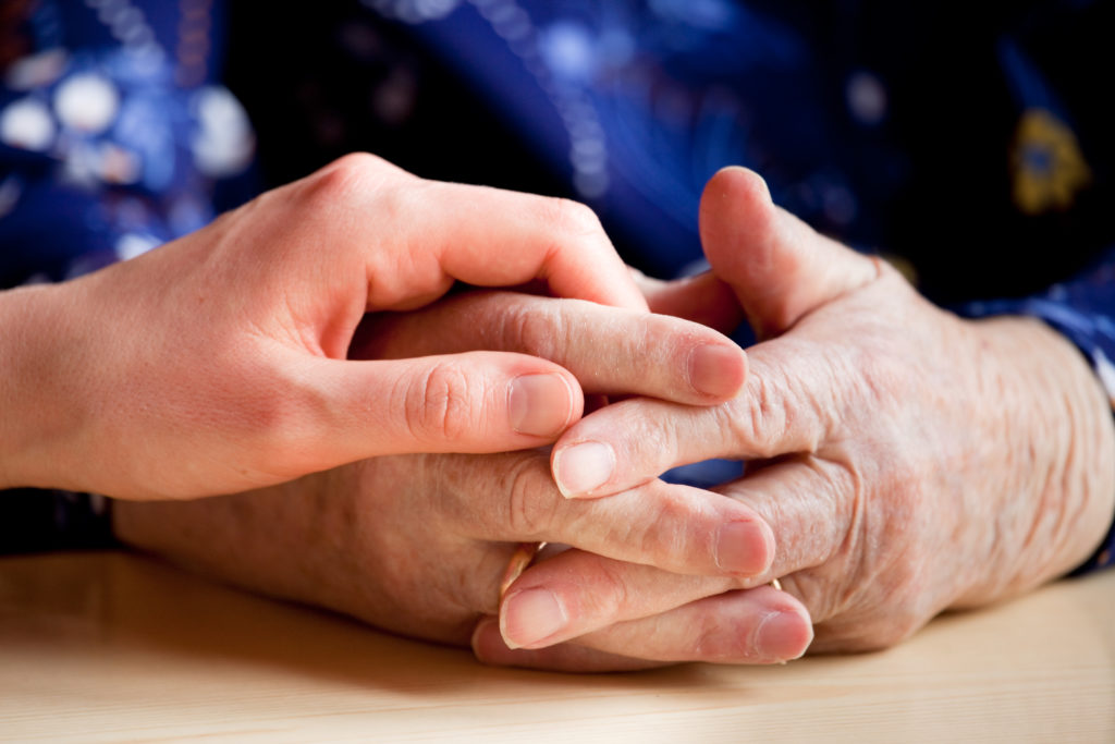 En ung hand håller i en äldre persons händer