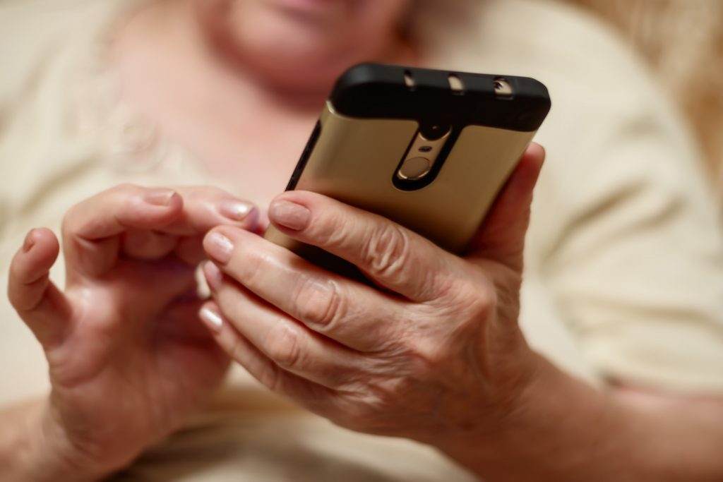 Äldre kvinnas händer och en mobiltelefon