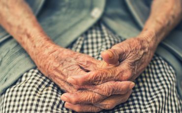äldre persons händer i knät