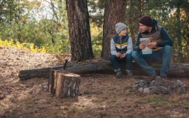 Pojke tillsammans med vuxen sitter och pratar i skogen